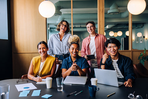 Group of diverse office professionals smiling and posing together in a meeting room
