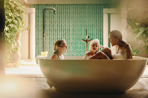 Happy family enjoying a fun bath time outdoors in a large bathtub on a sunny day