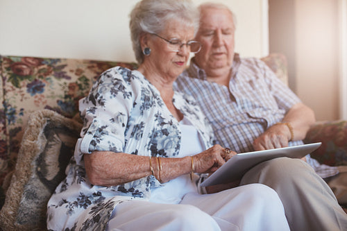 Senior couple using digital tablet at home