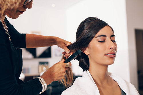 Female hair stylist working on a woman 's hair at salon