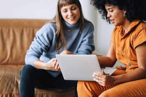 Happy young businesswomen using a laptop together in an office lobby
