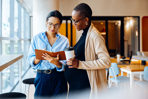 Two coworkers discussing and reviewing documents in an office setting