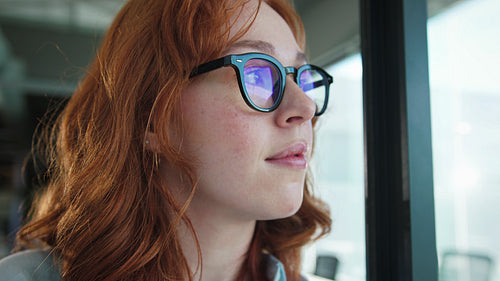 Business woman looking outside a window in an office