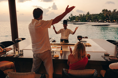 Chef entertaining guests at luxury teppanyaki restaurant during sunset