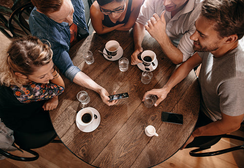 Group of friends at the cafe and looking at smart phone