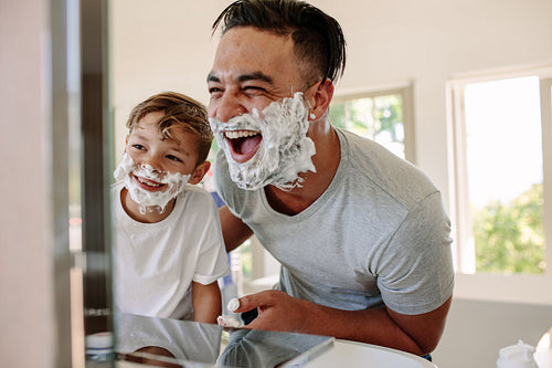 Happy father and son having fun while shaving