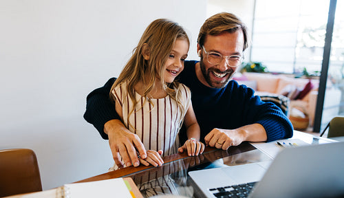 Man and girl share a learning moment at laptop