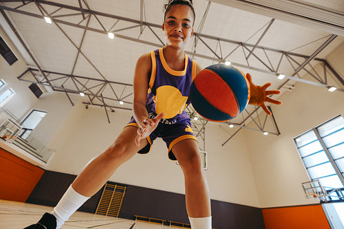 Young female athlete dribbling basketball in a spacious recreational gymnasium