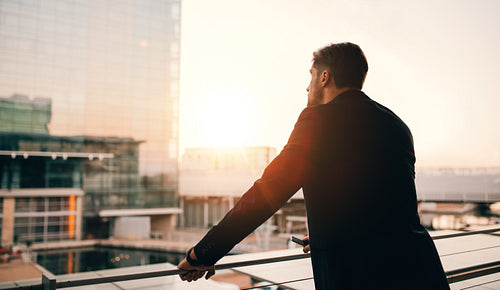 Businessman standing in airport lounge balcony and looking outside