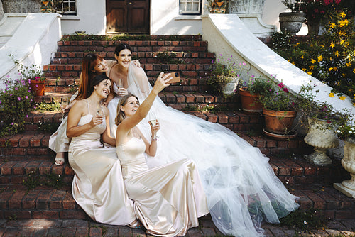 Bridal party capturing a joyful selfie during an outdoor wedding celebration