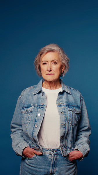Happy senior woman laughing in studio portrait on blue background, denim jacket and jeans, vertical video