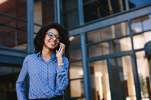 Businesswoman standing outside office building talking over mobile phone