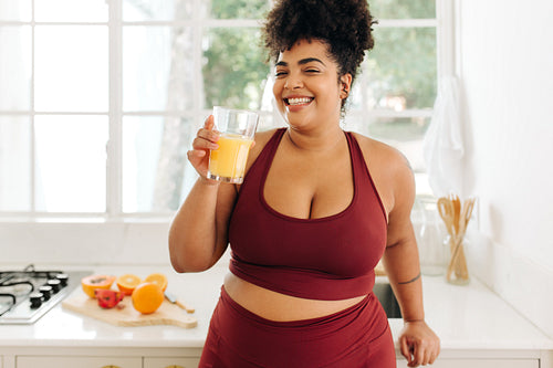 Plus size woman having a glass of juice at home