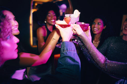 Group of friends sharing cocktails and laughing during a lively night out