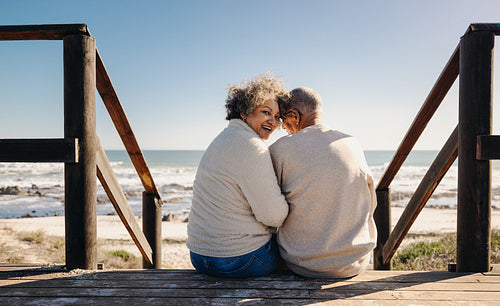 Cheerful senior woman smiling at the camera while sitting with her husband