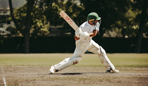 Cricketer in action hitting the ball on a sunny day