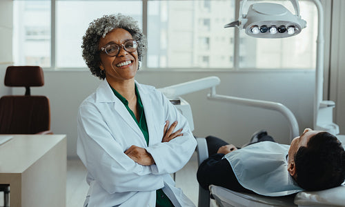 Confident dentist sits with her patient before treatment in the clinic