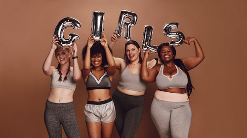 Multi-ethnic women with girl word in balloon letters