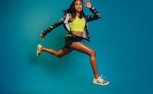 Female runner training on blue background