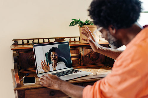 Mature man waving and greeting online during a video chat with his wife
