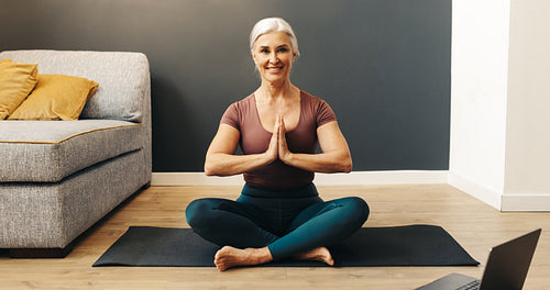 Happy senior woman practicing yoga, meditating in prayer pose