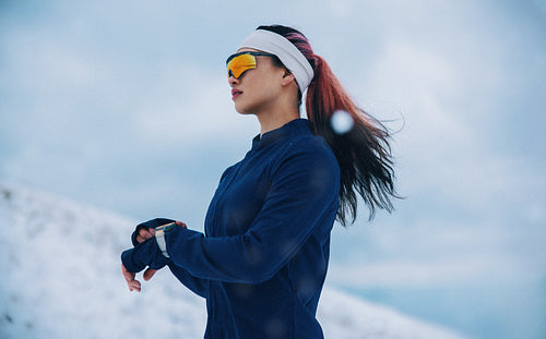 Runner checks smartwatch during winter training in a snowy outdoor workout scene