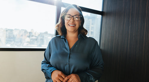 Smiling woman standing confidently in office near window
