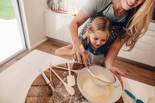 Woman with her daughter making batter in kitchen