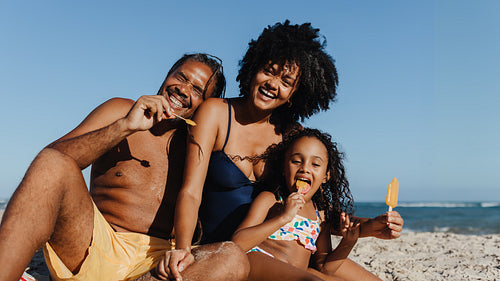 Happy family enjoying summer vacation at the beach with ice cream treats