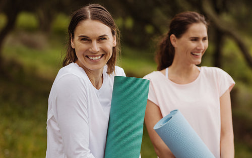 Women with fitness mats standing in a park