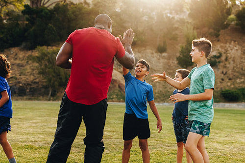 Rugby coach doing a high five with his elementary school team