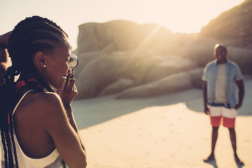 Beautiful woman taking picture of her boyfriend at beach