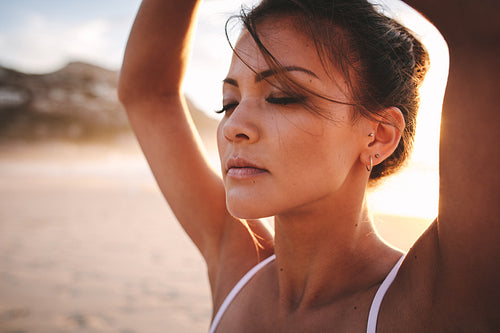 Fit woman sitting on beach and meditating