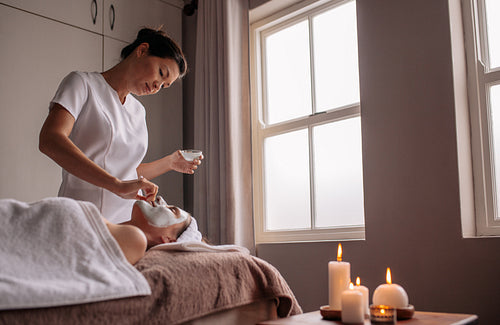 Woman receiving face mask treatment in spa 