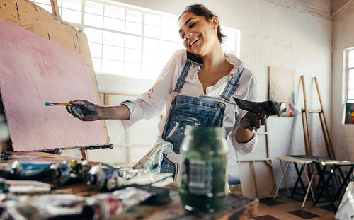 Freelance painter taking a phone call in her art studio