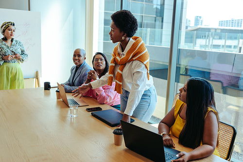 Black woman leading a discussion in a modern boardroom setting with all-female board members