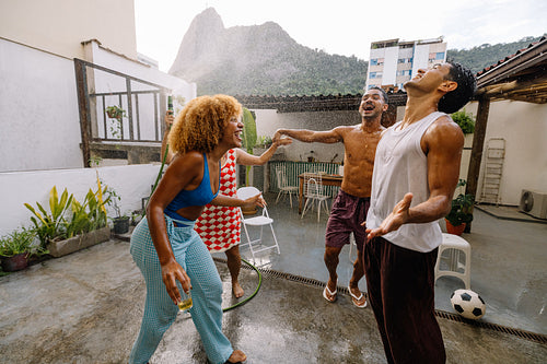 Four friends dancing in the spray of a hose bath in Rio