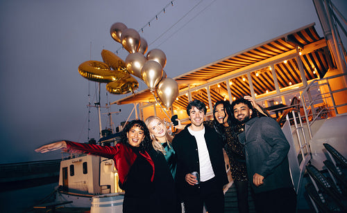 Group of friends celebrating on a boat at night with balloons