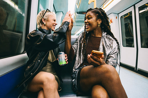Public transport fun, women high-fiving on the metro train