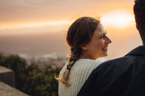 Cheerful woman sitting with her boyfriend outdoors