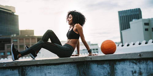 Female athlete relaxing on the rooftop fence