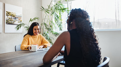 Two professional women discussing architectural plans in a bright modern office space