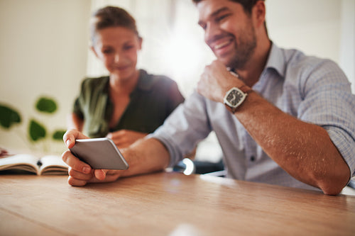 Couple sitting together at table using mobile phone