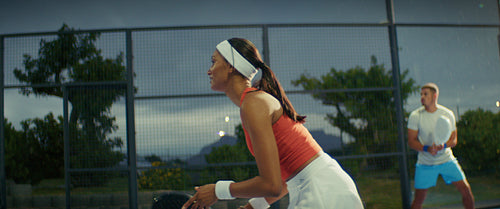 Female padel player showcasing skill and agility during a competitive sports match at night