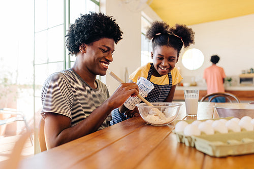 Happy siblings mixing the ingredients for baking a traditional Brazilian cake at home