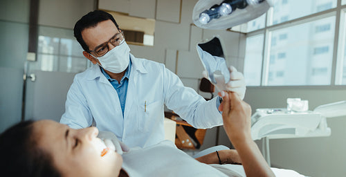 Dentist reviewing treatment with patient using dental mirror