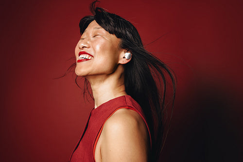 Joyful woman enjoying high-quality sound with earbuds in studio portrait