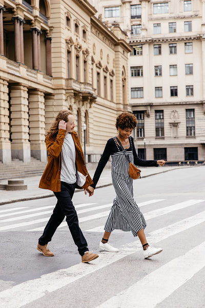 Affectionate couple holding hands crossing city street together