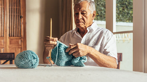 Retired senior man knitting warm clothes 