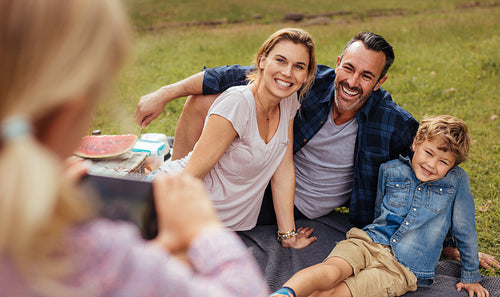 Little girl photographing family during picnic at park